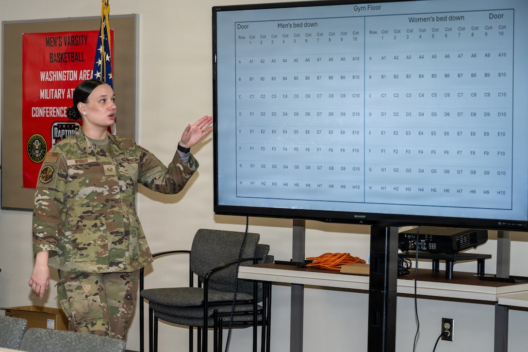 An Airman gestures to a screen with words on it.