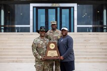 From left, Lt. Gen. Kevin D. Admiral, Commanding General of the III Armored Corps and Fort Hood, Sgt. 1st Class Leroy Betts, and Claude Mathis, head football coach of DeSoto High School pose on the steps of the III Armored Corps headquarters at Fort Hood, Texas