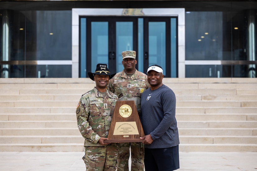 From left, Lt. Gen. Kevin D. Admiral, Commanding General of the III Armored Corps and Fort Hood, Sgt. 1st Class Leroy Betts, and Claude Mathis, head football coach of DeSoto High School pose on the steps of the III Armored Corps headquarters at Fort Hood, Texas