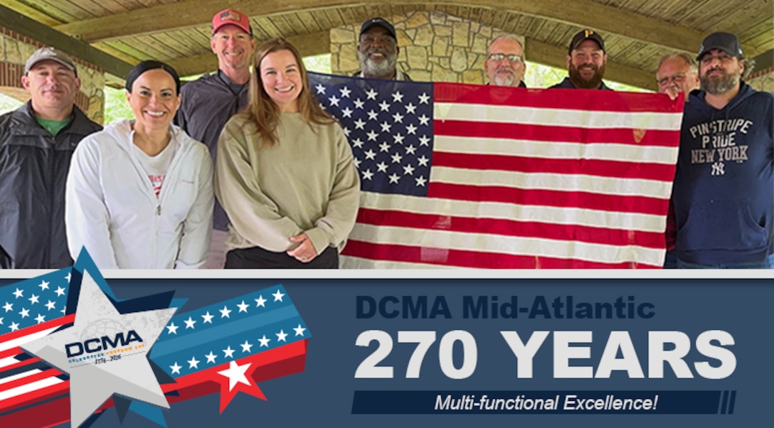 A group poses for a photo outdoors under covered picnic area.