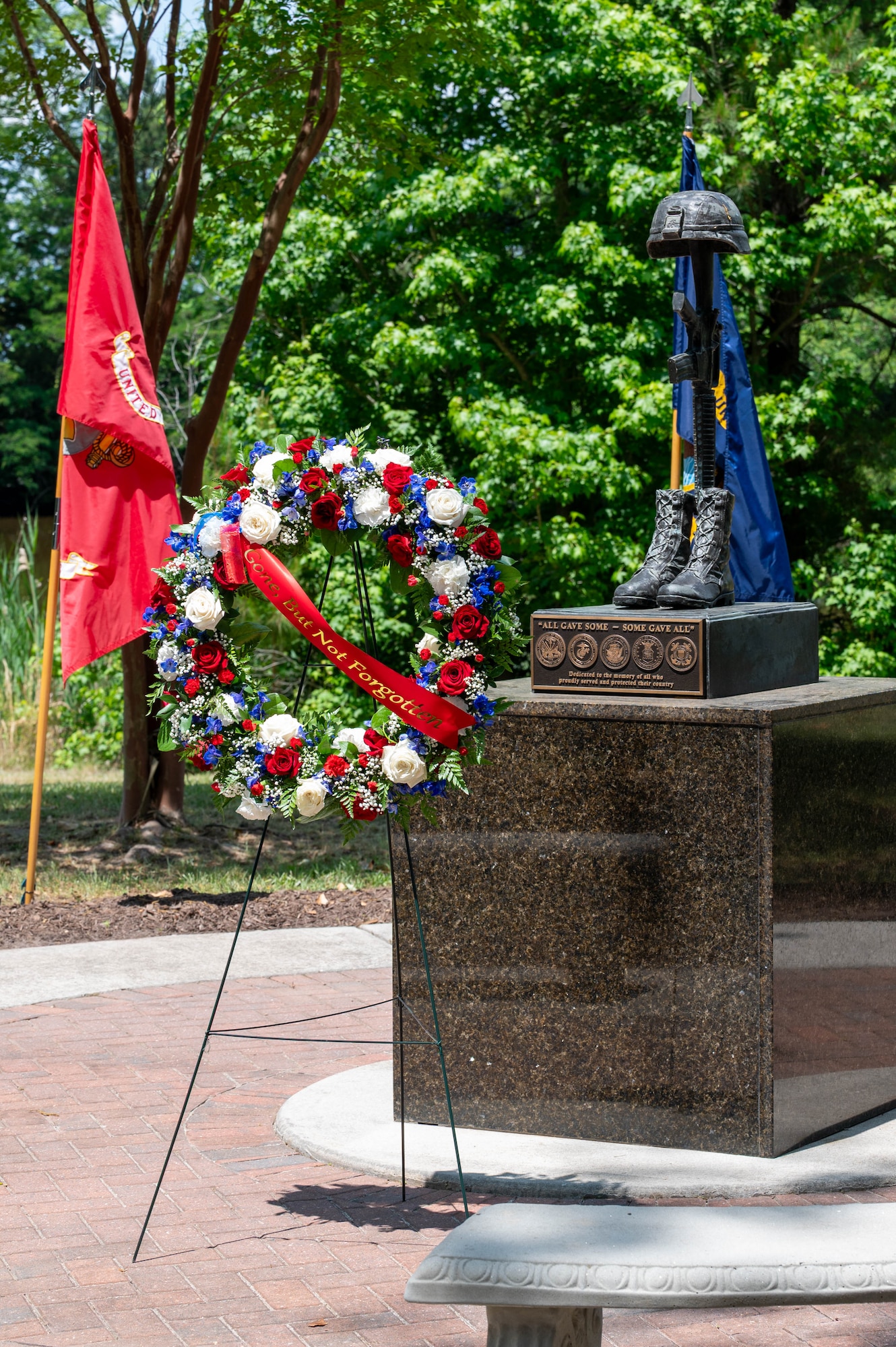 Photo of a ceremonial wreath on a stand in front of a fallen soldier statue.