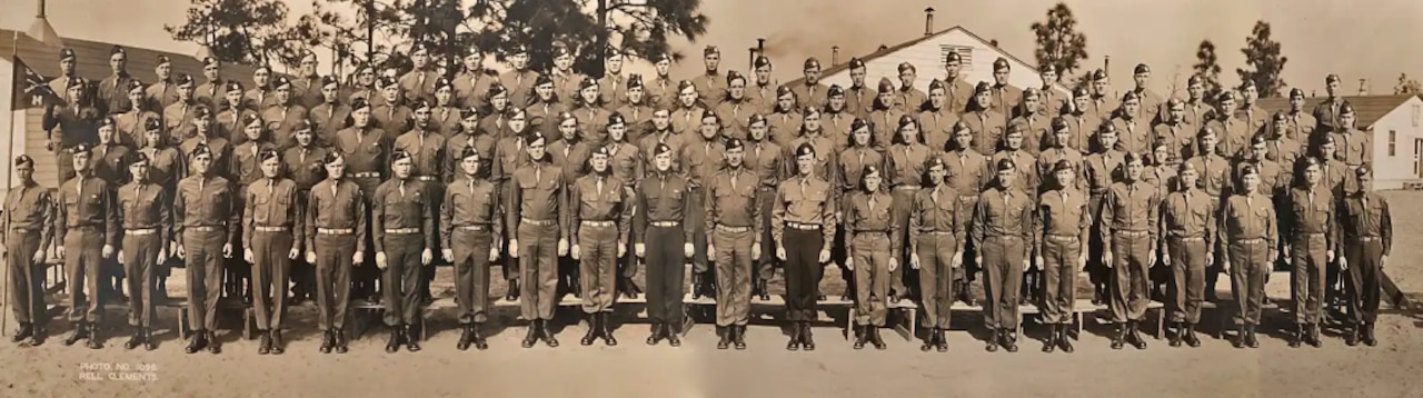 Soldiers wearing Army khakis stand on bleachers and pose for a photo.