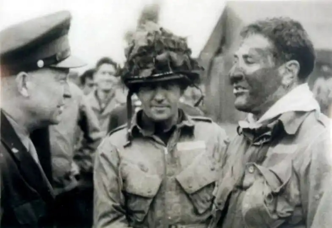 Three men wearing military uniforms are pictured chatting.