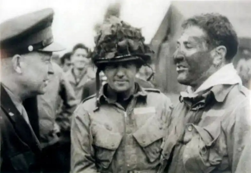 Three men wearing military uniforms are pictured chatting.
