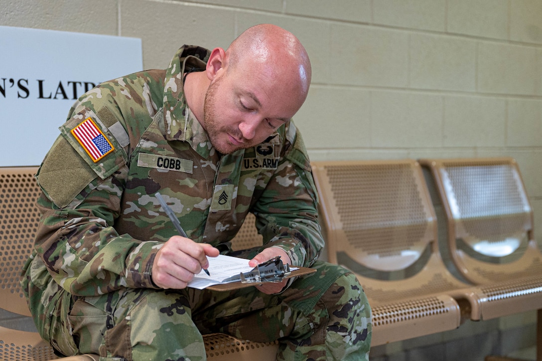 Photo of a solider sitting filling out paperwork.