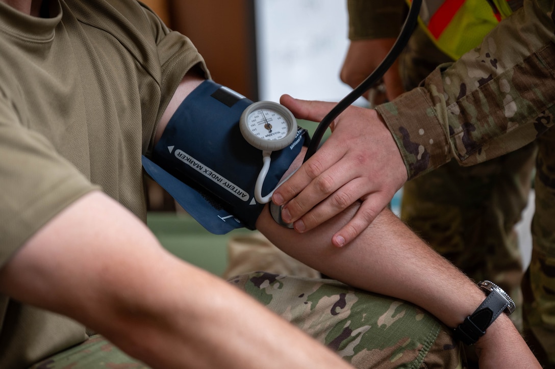 Up close photo of a service member taking the blood pressure of another member.