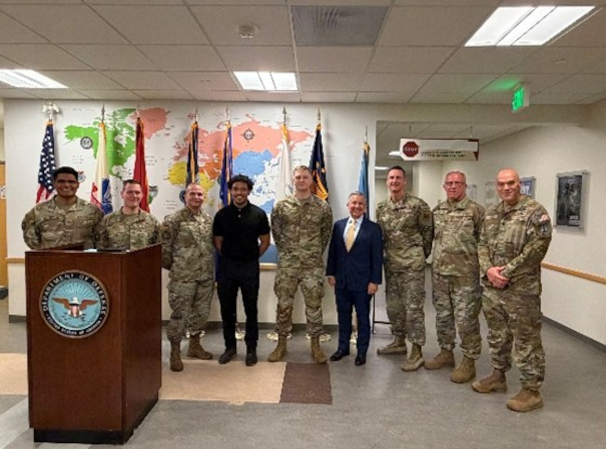 Peter I. Belk, principal deputy assistant secretary of war for readiness, stands with members of the 343d Recruiting Squadron at the Fort Snelling Military Entrance Processing Station in Minneapolis, Minn., on May 26, 2026