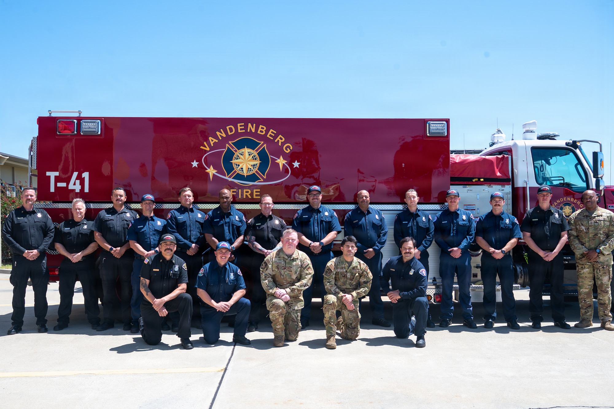 A group of people pose for a photo outside in front of a firetruck.
