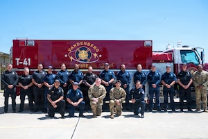 A group of people pose for a photo outside in front of a firetruck.
