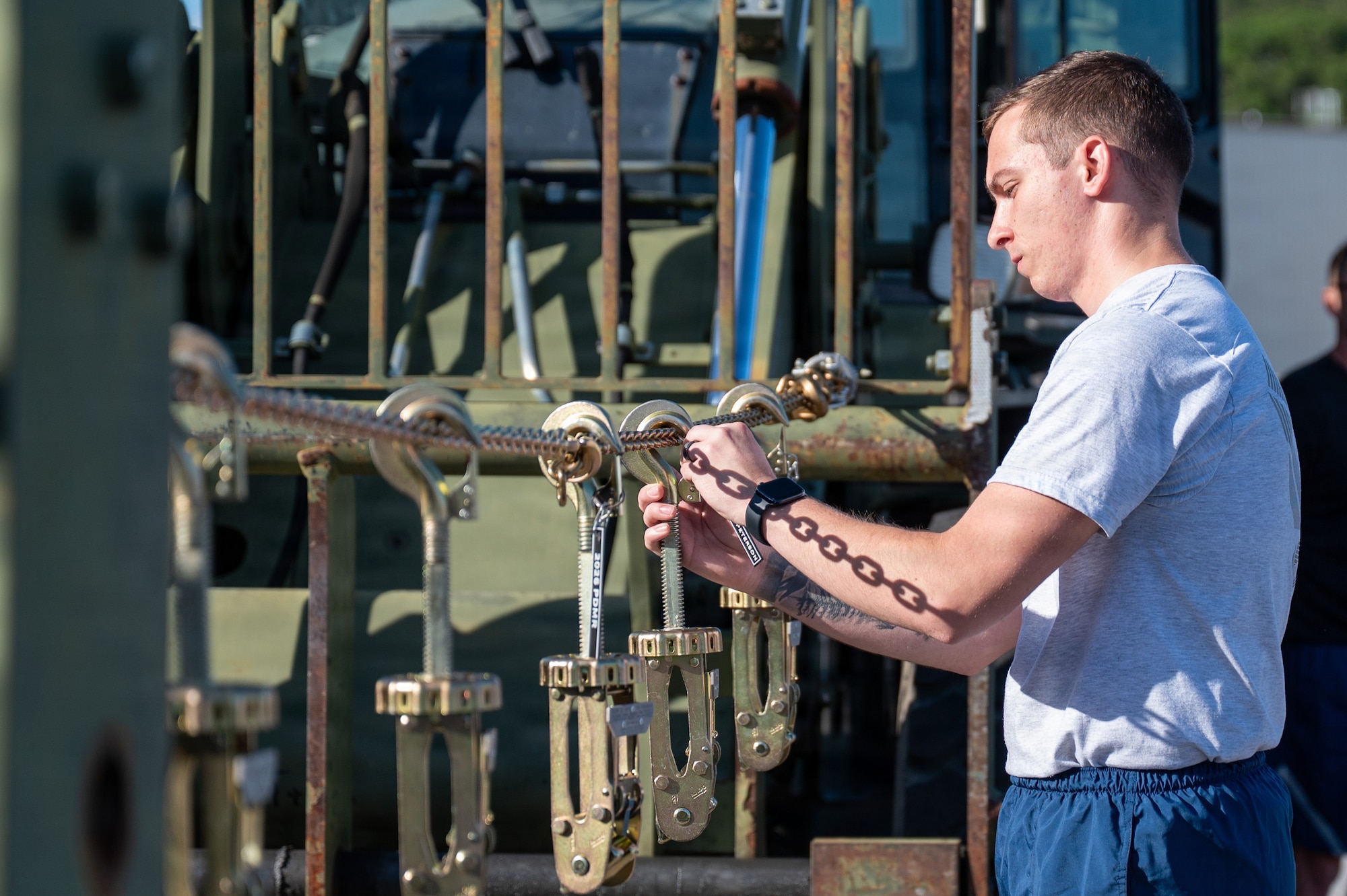 An Airman hangs a tie-down clamp.