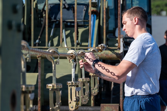 An Airman hangs a tie-down clamp.