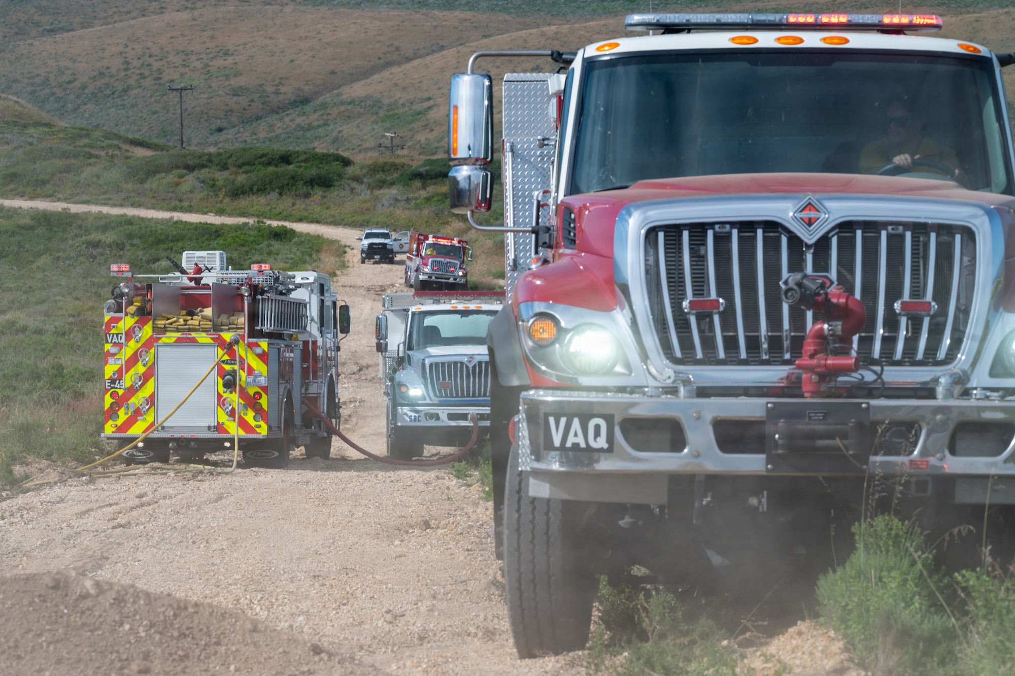 Firetrucks on a dirt road positioned on the side.
