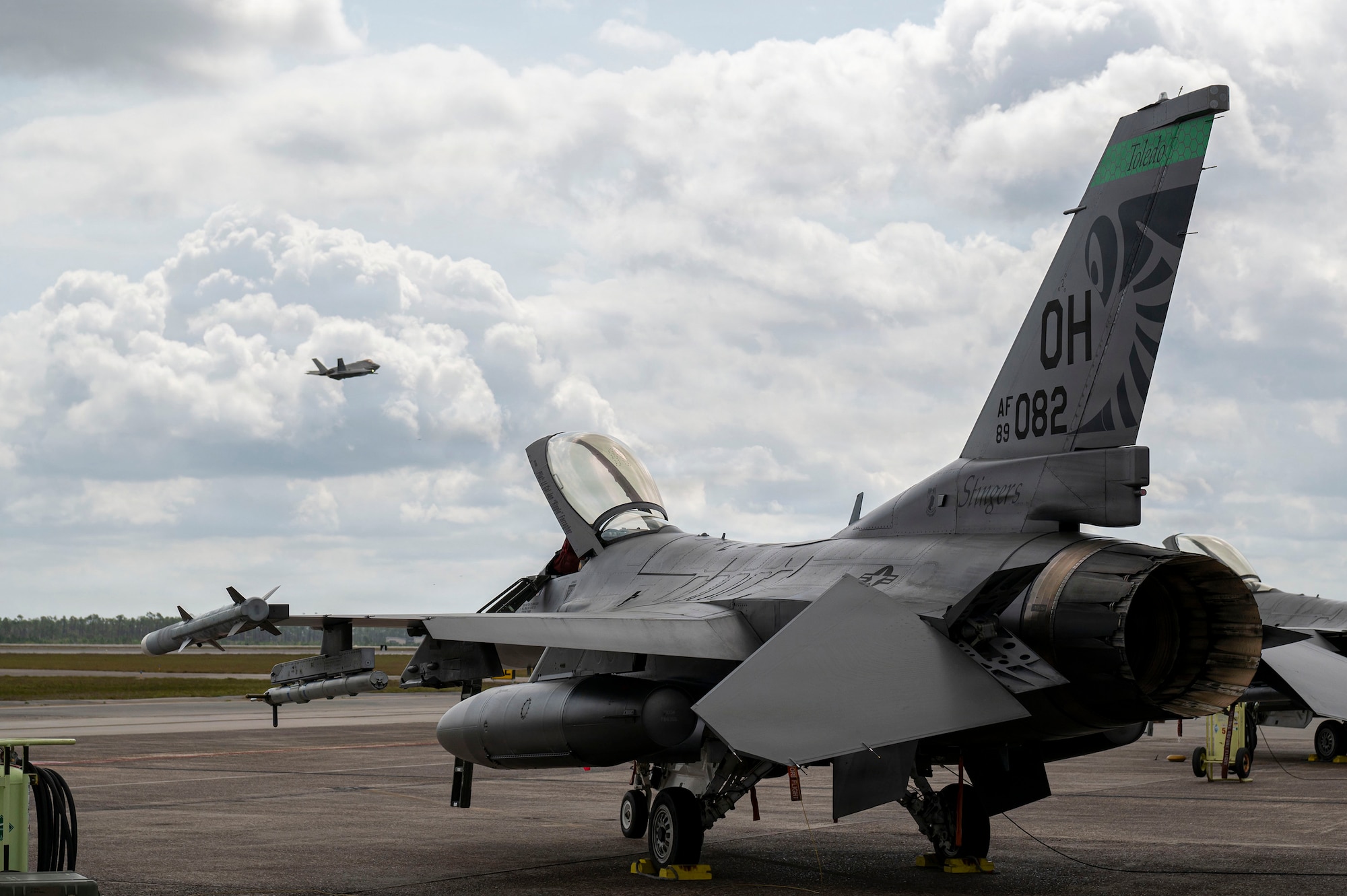 A U.S. Air Force F-16 Fighting Falcon assigned to the Ohio National Guard’s 180th Fighter Wing sits on the flight line as an F-35 Lightning II assigned to the 325th Fighter Wing takes off during Checkered Flag 26-2 and the Weapons System Evaluation Program-East at Tyndall Air Force Base, Fla., April 29, 2026.