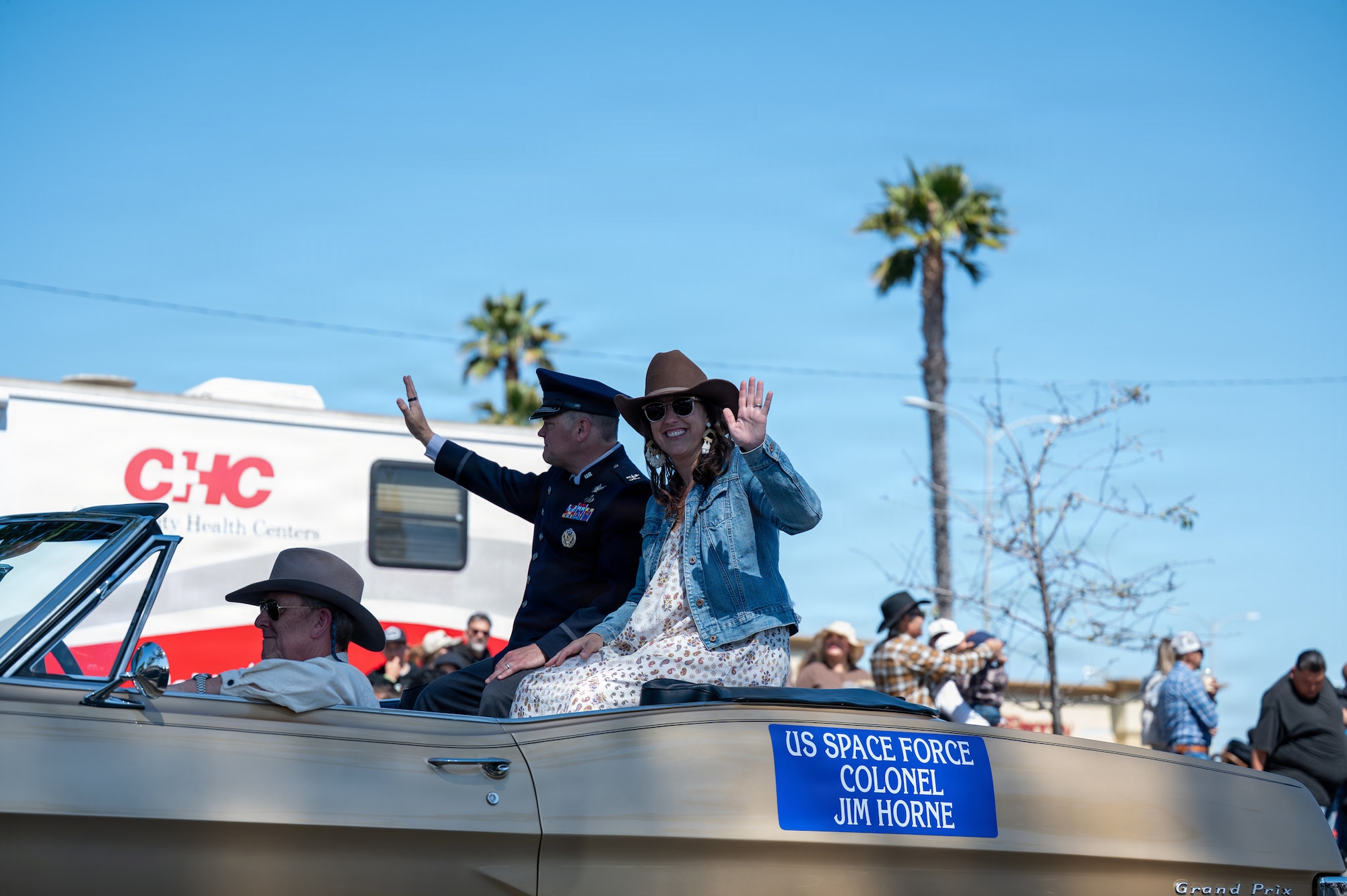 Man and woman sit in open convertible car.