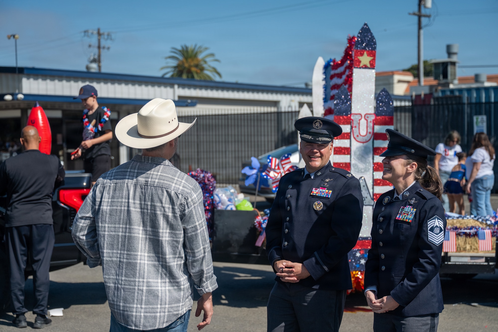 Two military troops talk with a man in cowboy hat.