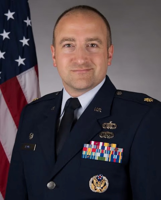 Major Lewis in Service Dress in front of an American Flag background.