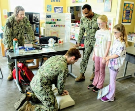 Hospital Corpsman 2nd Class Daniel Strunk, a Radiology Technician, guides local homeschool students through an interactive medical demonstration as students look on alongside Hospital Corpsman 1st Class Sandra Zdunowski (left) and Hospital Corpsman 3rd Class Kerby Maurice (right), both serving as Biomedical Equipment Technicians (BMETs), during the Homeschool Share Fair at the Naval Air Station Patuxent River Youth Center. Personnel hosted hands-on stations showcasing dental hygiene, basic first aid, and specialized technical fields to engage military families and foster curiosity about healthcare and naval service. Coordinated by NAS Patuxent River School Liaison Officer Dawn Simpson, the event connected local homeschooling families with base resources and support services.