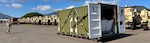 The FORGE Rapid Deployment Hybrid Microgrid (RDHM) system is positioned alongside tactical military vehicles during a field exercise. The containerized system is designed to provide resilient, expeditionary power that can be rapidly deployed in support of military operations.