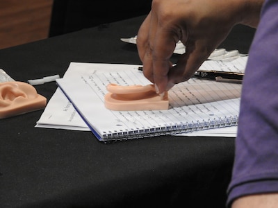 A hand performing dry needling techniques on a 3D outer ear