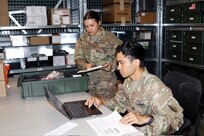 Two Soldiers work in a medical supply hub.