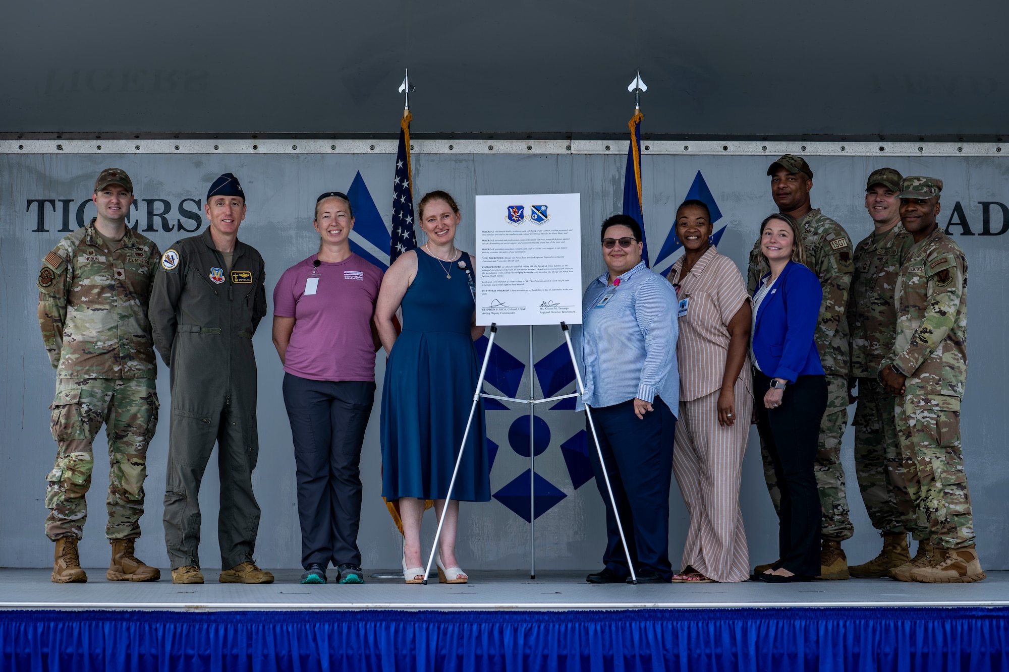 U.S. Air Force airmen and community members pose next to signed proclamation.