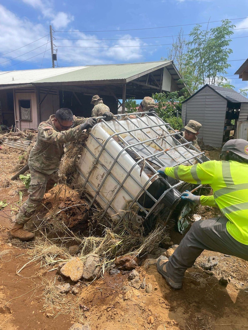 Hawaii National Guard members removing downed trees, rocks and debris from homes, helping make them safe and accessible again.