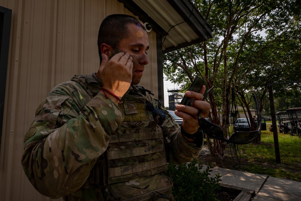 Airman putting on camouflage.
