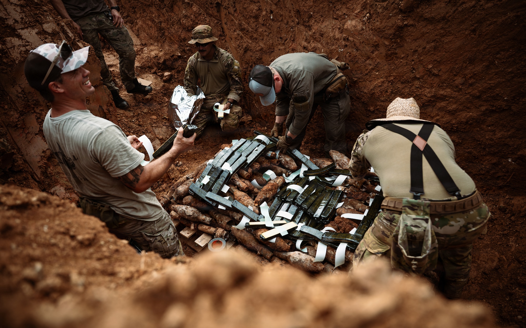 Disposal technicians arm C-4 on a pile of exploded ordnance.