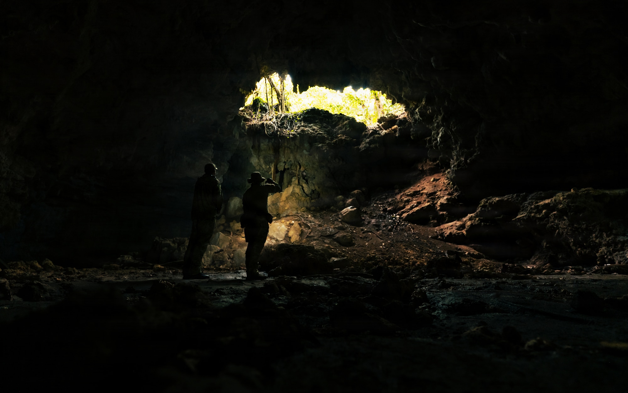 A technician search a cave for simulated unexploded ordnance.