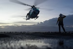 A sailor assigned to the San Antonio-class amphibious transport dock USS Fort Lauderdale gives a send-off salute as a U.S. Marine Corps UH-1Y takes off during night deck landing qualifications while underway in the Caribbean Sea, May 19, 2026, while in support of Operation Southern Spear.