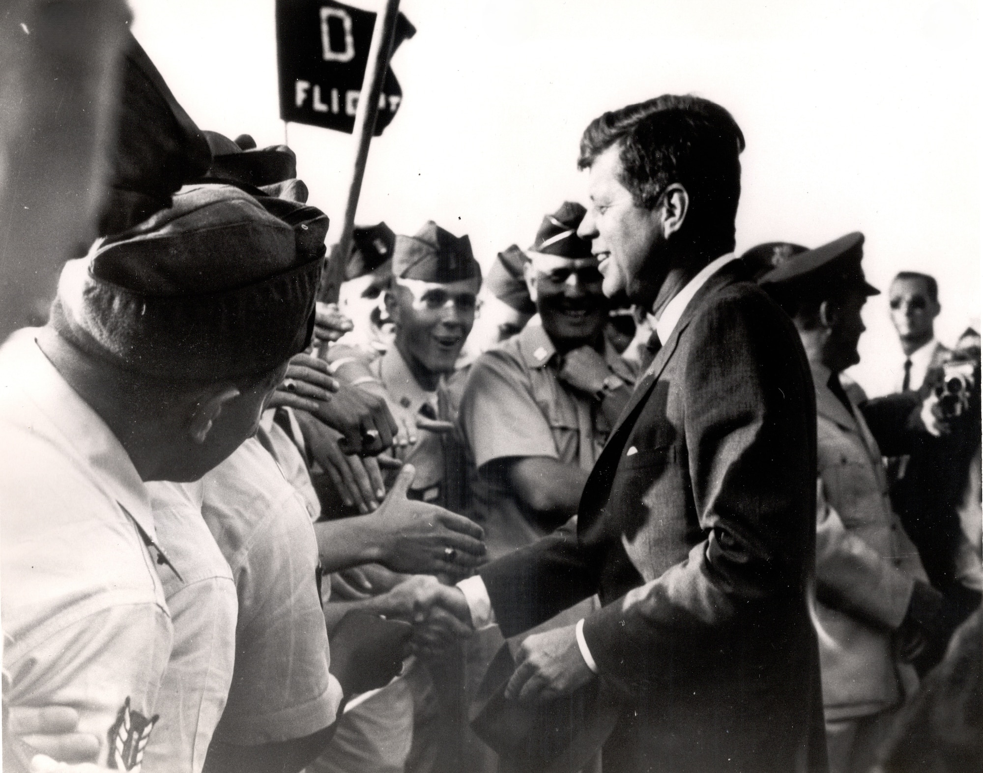 The late President John F. Kennedy taking with AFROTC cadets, members of D Flight, first period Summer Training Unit 1962 at Otis AFB, Mass Tactical Officer of D Flight, Captain Healy, is in the background. (Courtesy Photo)