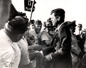 The late President John F. Kennedy taking with AFROTC cadets, members of D Flight, first period Summer Training Unit 1962 at Otis AFB, Mass Tactical Officer of D Flight, Captain Healy, is in the background. (Courtesy Photo)