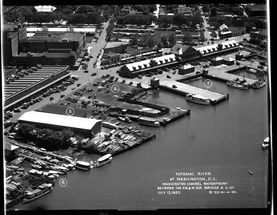 A high-angle aerial view of the waterfront with numbered markers indicating: (4) a boat basin, (5) a large warehouse, (6) a parking area, and (7) piers. The Municipal Fish Market is clearly visible. Also visible are the businesses: National City Dairy Co.; General Poultry Co.; C. Engels Sons; Columbia Hotel Supply Co.; National Bank of Washington; an Esso gas station; and a luncheonette serving Wilkins Coffee.