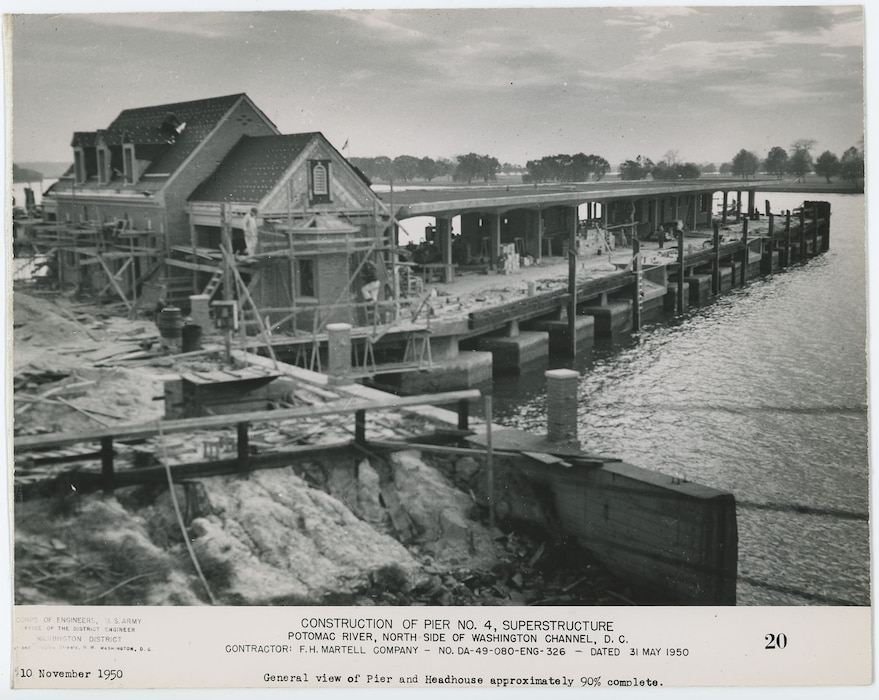 The pier and adjacent headhouse rise above the water, with scaffolding, construction materials, and shoreline structures visible. Corps of Engineers, U.S. Army, Office of the District Engineer, Washington District, First and Douglas Streets, N.W., Washington.