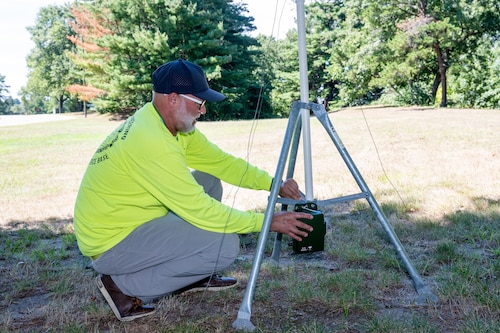 Image of a person setting up an audio recording device on a stand.