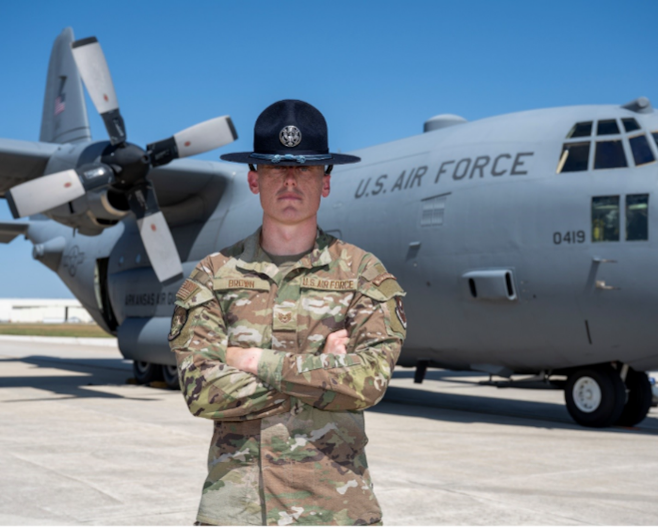 U.S. Air Force Tech. Sgt. Nathaniel Brown, 322nd Training Squadron master military training instructor, poses in front of a C-130H Hercules at Kelly Field, Joint Base San Antonio-Lackland, Texas, Aug. 24, 2026. Brown, who was a crew chief prior to retraining into the military training instructor career field, marshalled the C-130 crew as they parked after landing at Kelly Field. (U.S. Air Force photo by Marcus Robins)