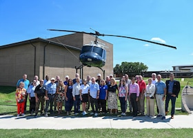 A group of people standing in front of a parked helicopter.