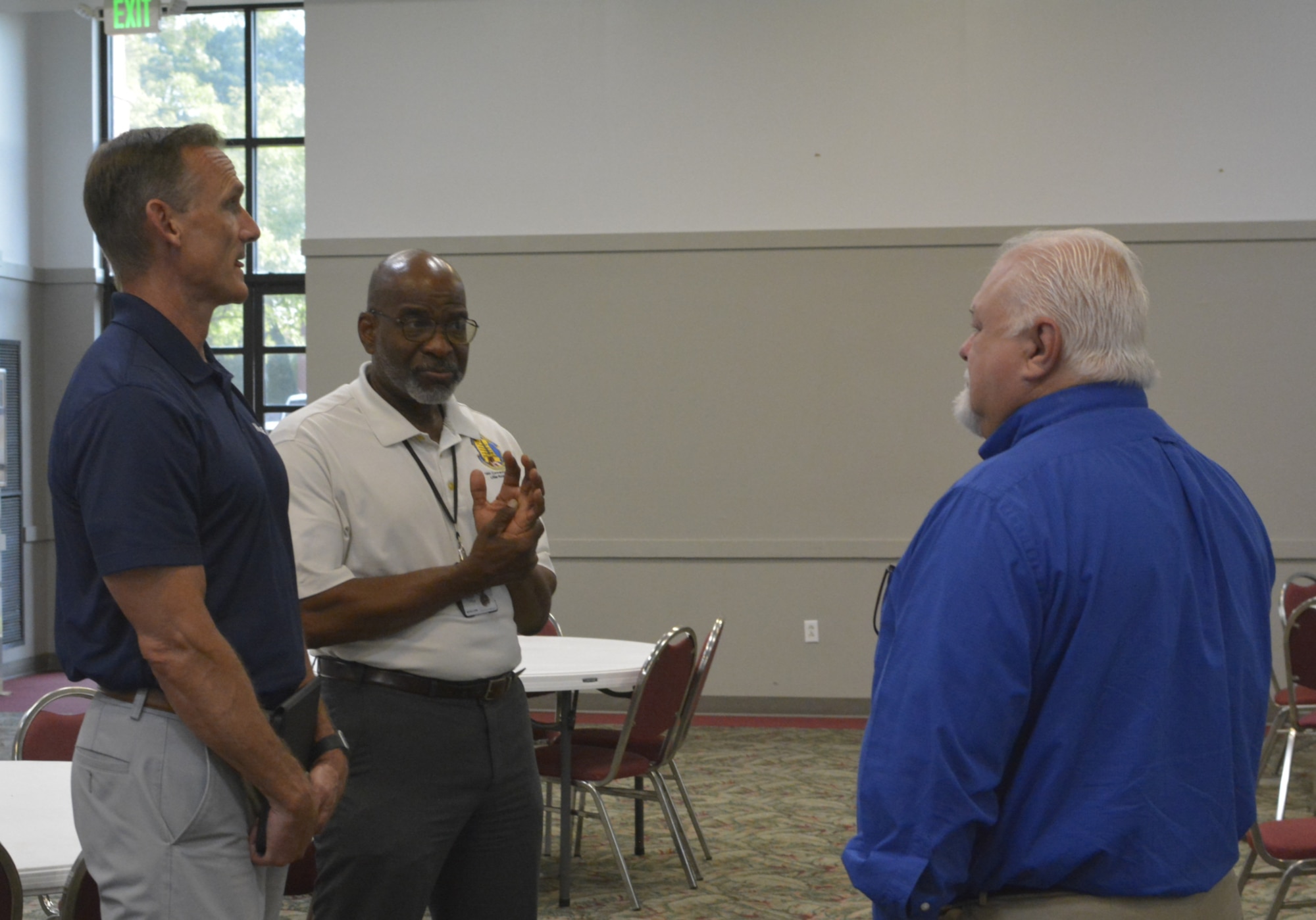 Three men talk.