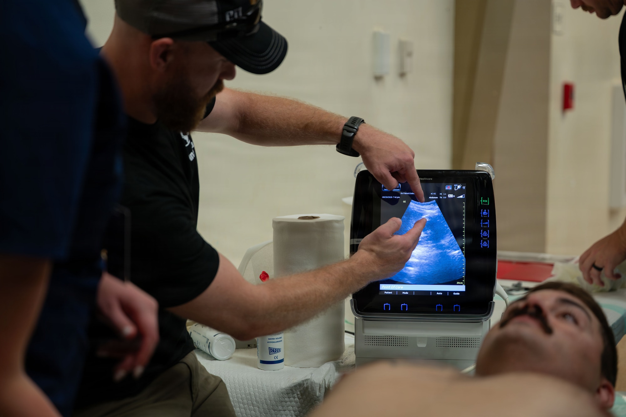A Global Training Institute instructor points to an ultrasound display screen while demonstrating imaging techniques to students.