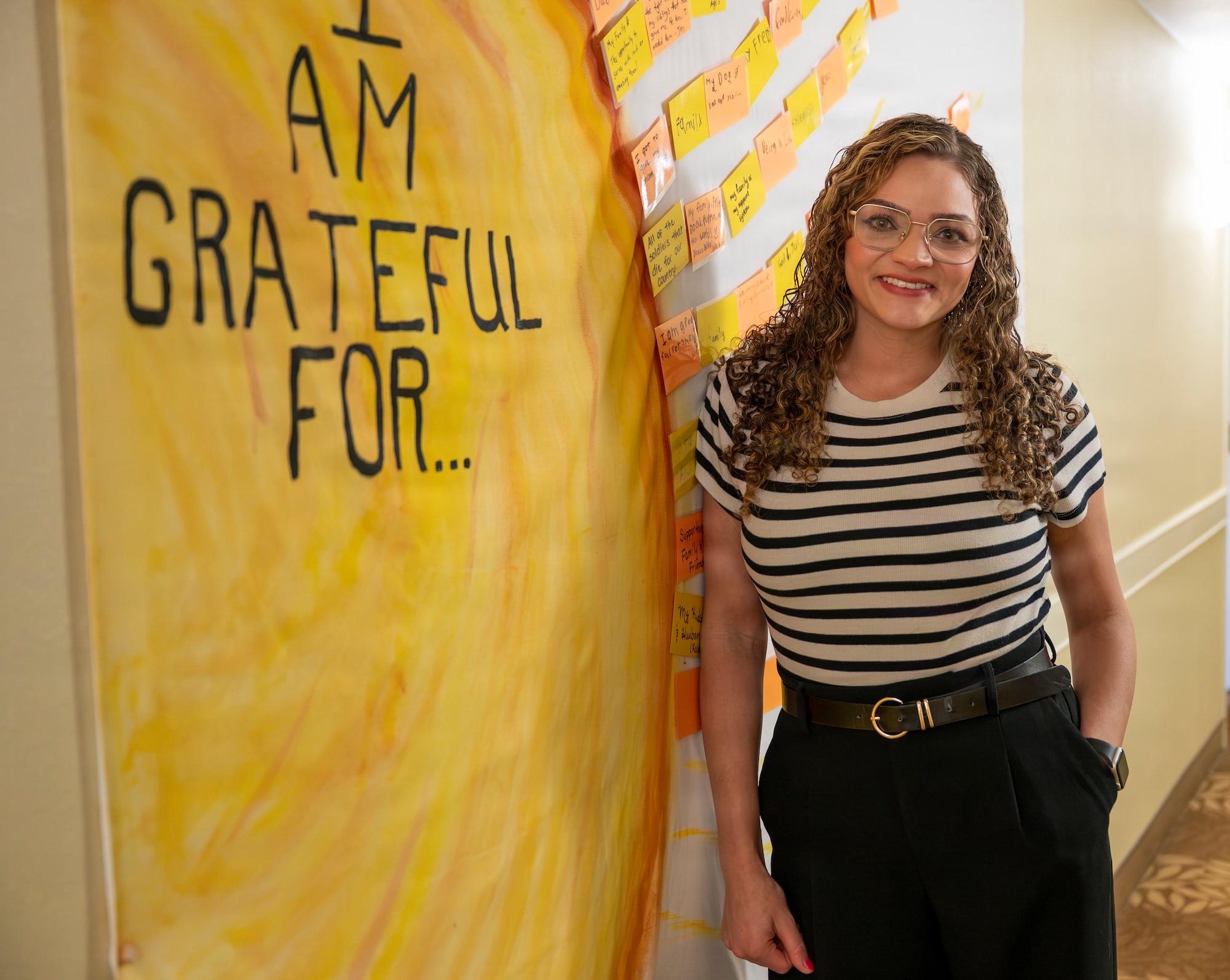 A woman leans against a wall with a yellow poster on it