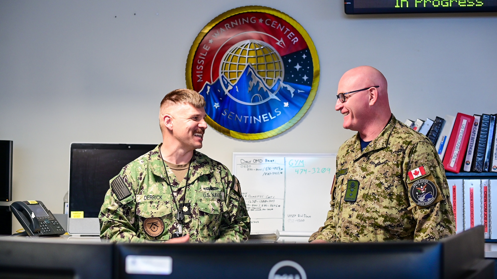 Lt. Cmdr. Jeremiah Derrick, left, shares a laugh with Maj. Gen. Kyle C. Paul, right, on the operations floor.