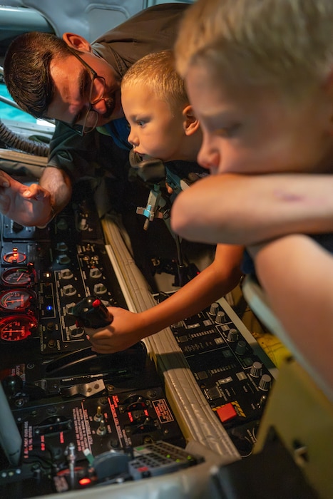 U.S. Air Force Staff Sgt. Zach Henderson, 54th Air Refueling Squadron instructor boom operator, teaches children how to operate the boom in a KC-135 Stratotanker simulator at Altus Air Force Base, Oklahoma, Aug. 31, 2026. The simulator experience gave families an opportunity to learn how boom operators help extend the range and endurance of U.S. and allied aircraft. (U.S. Air Force photo by Airman 1st Class Nathan Langston)