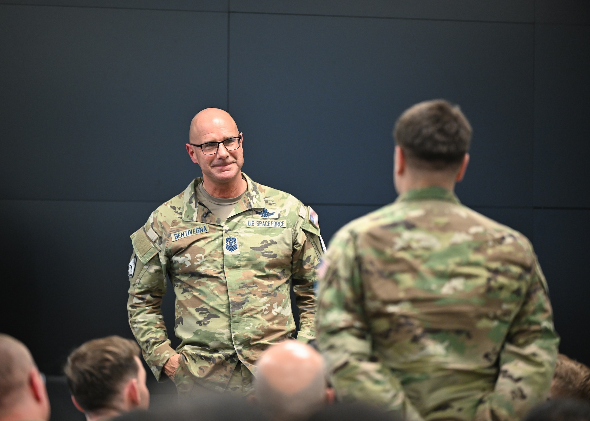 Chief Master Sgt. Bentivegna stands and listens to a member of an audience ask a question.
