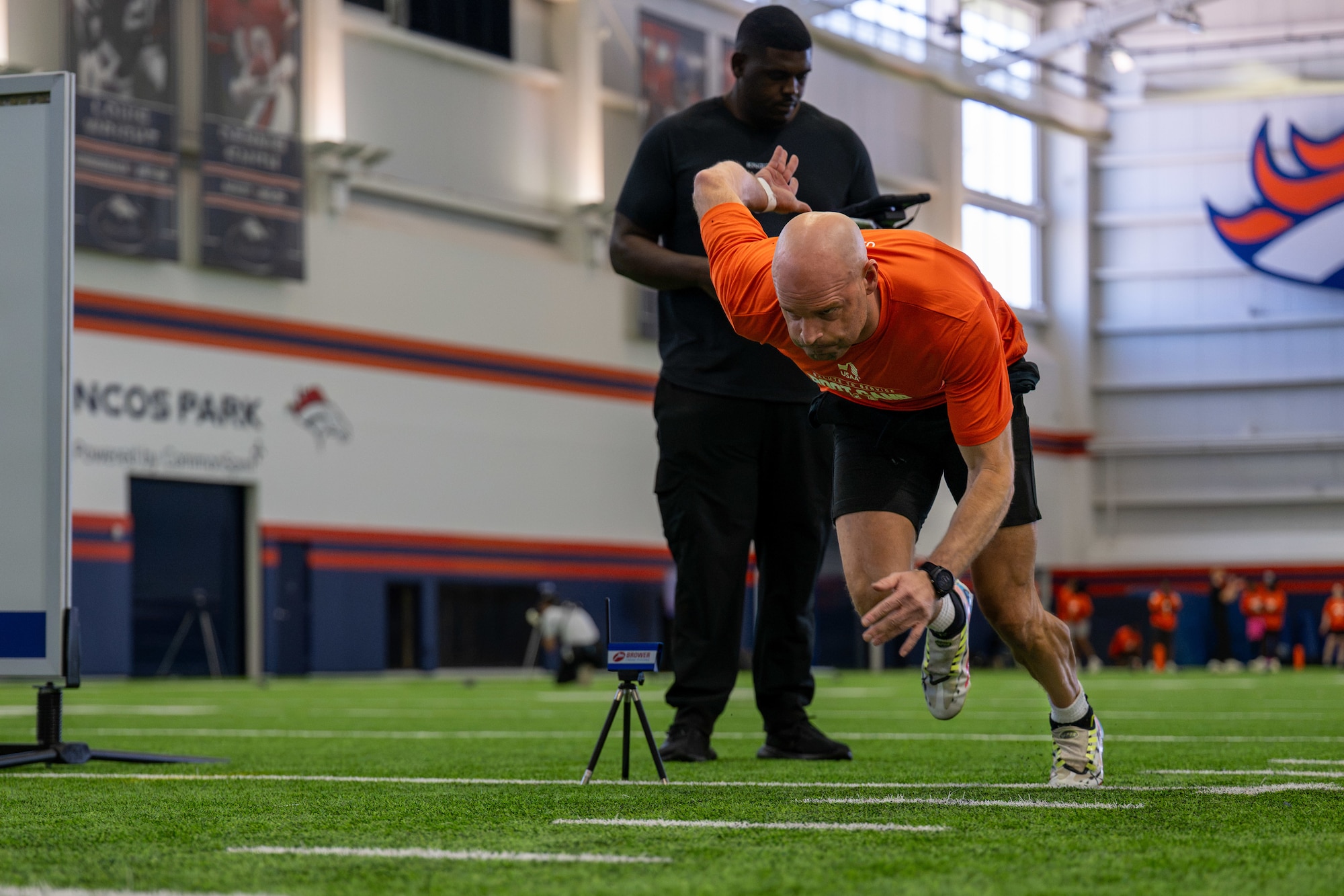man sprints while another man holds a clipboard