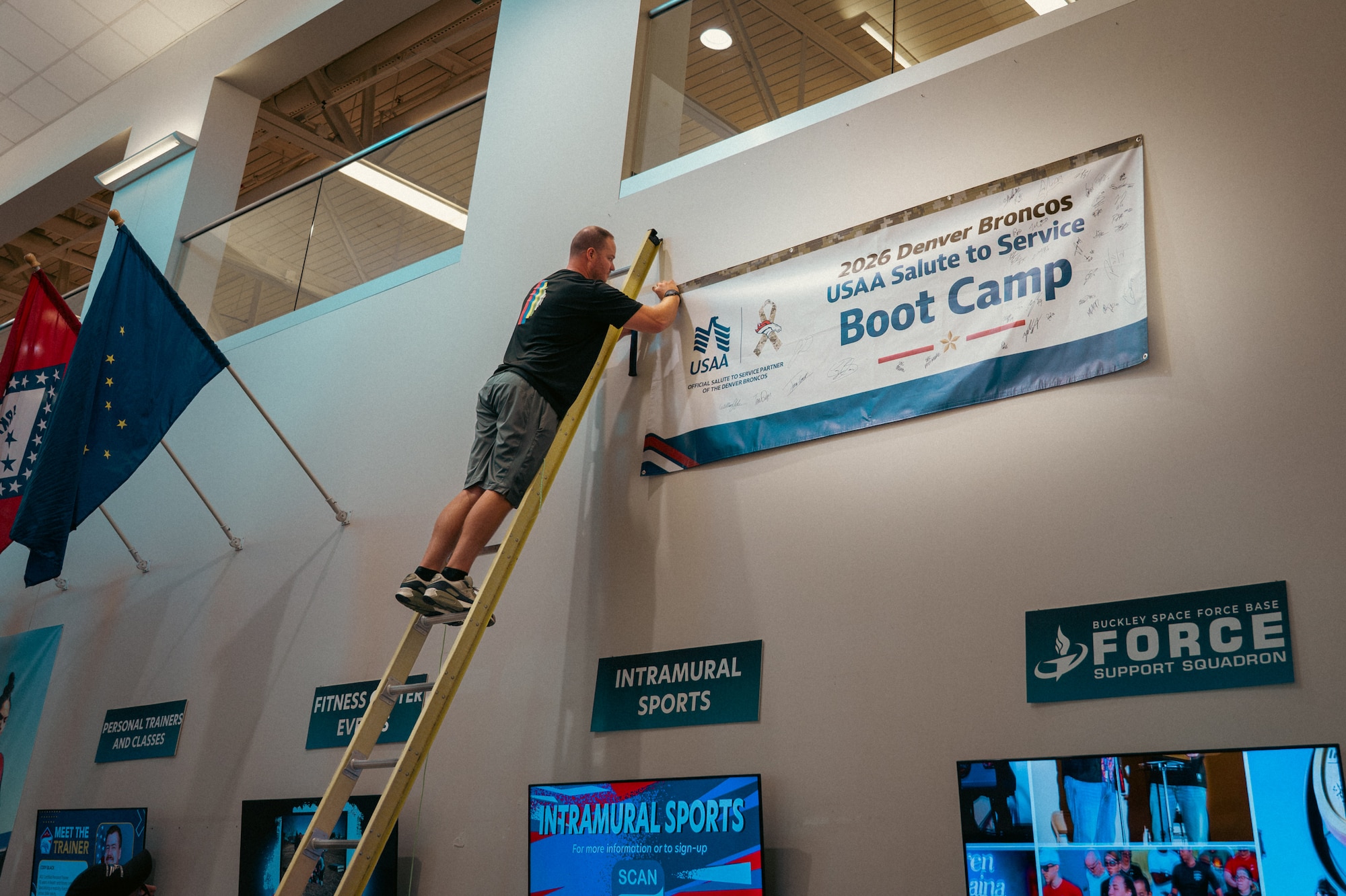 Man stands on a ladder while hanging a banner