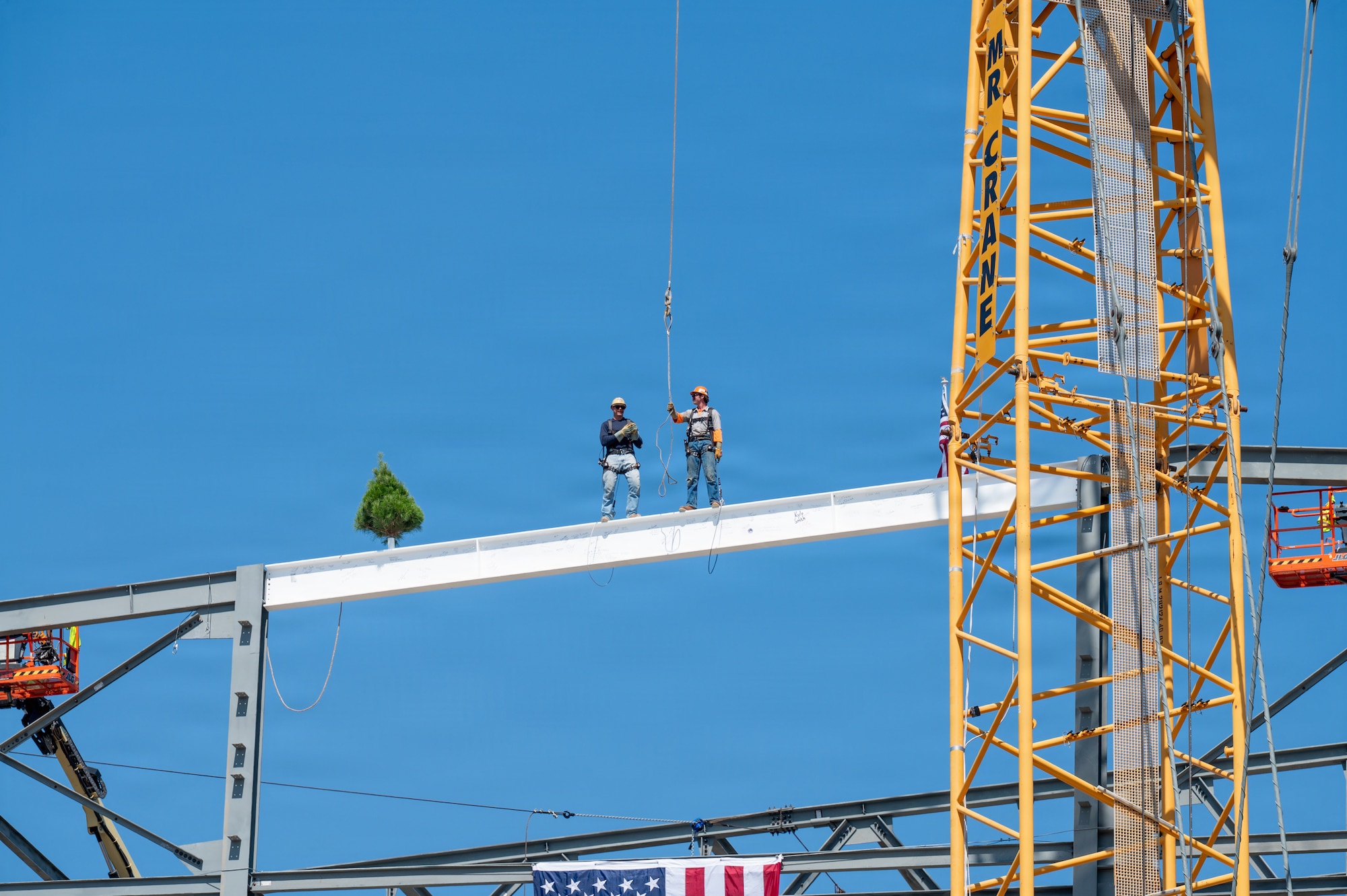 Two men stand on a steel beam.