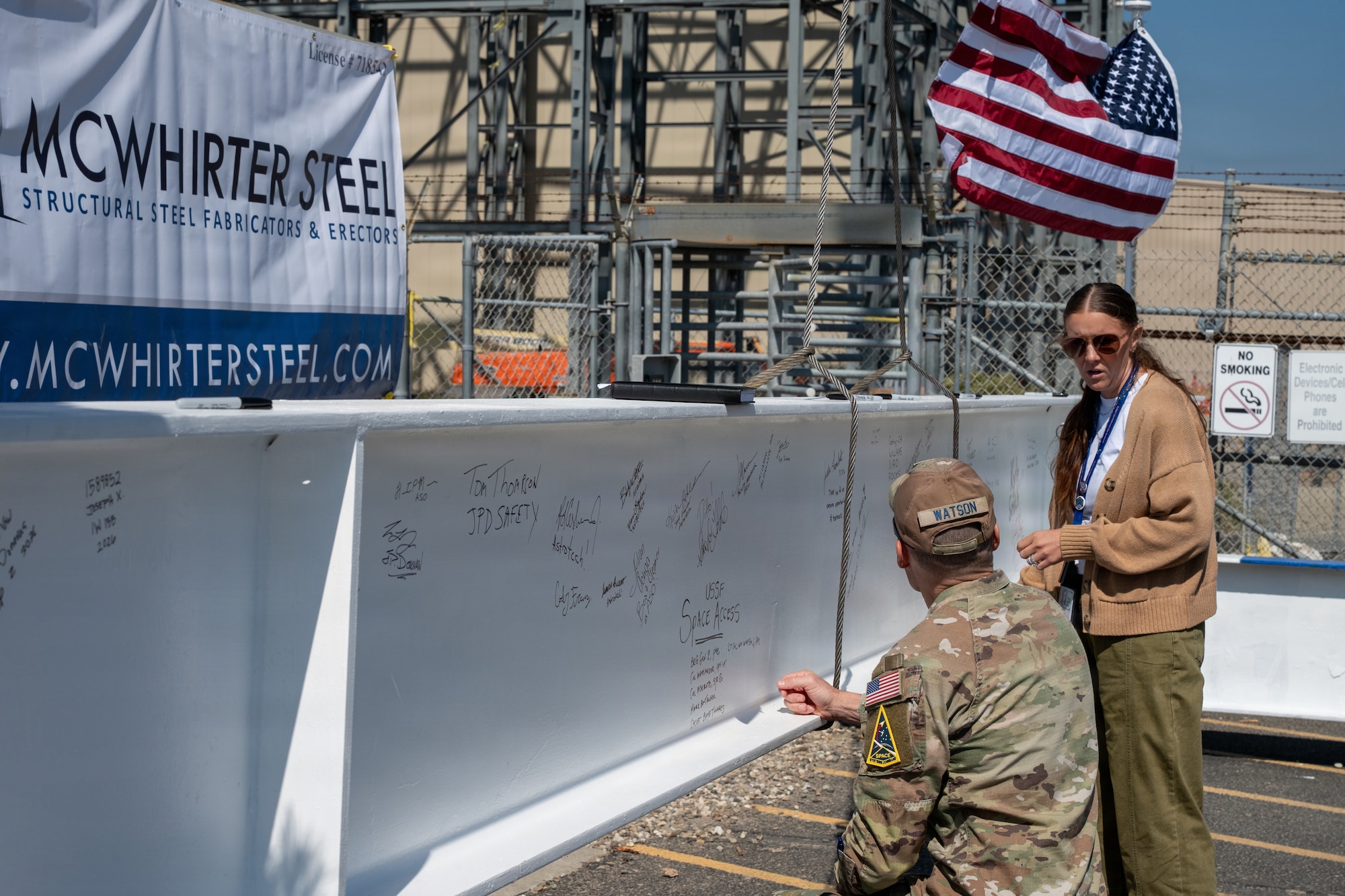 An officer signs a steel beam at a construction site.