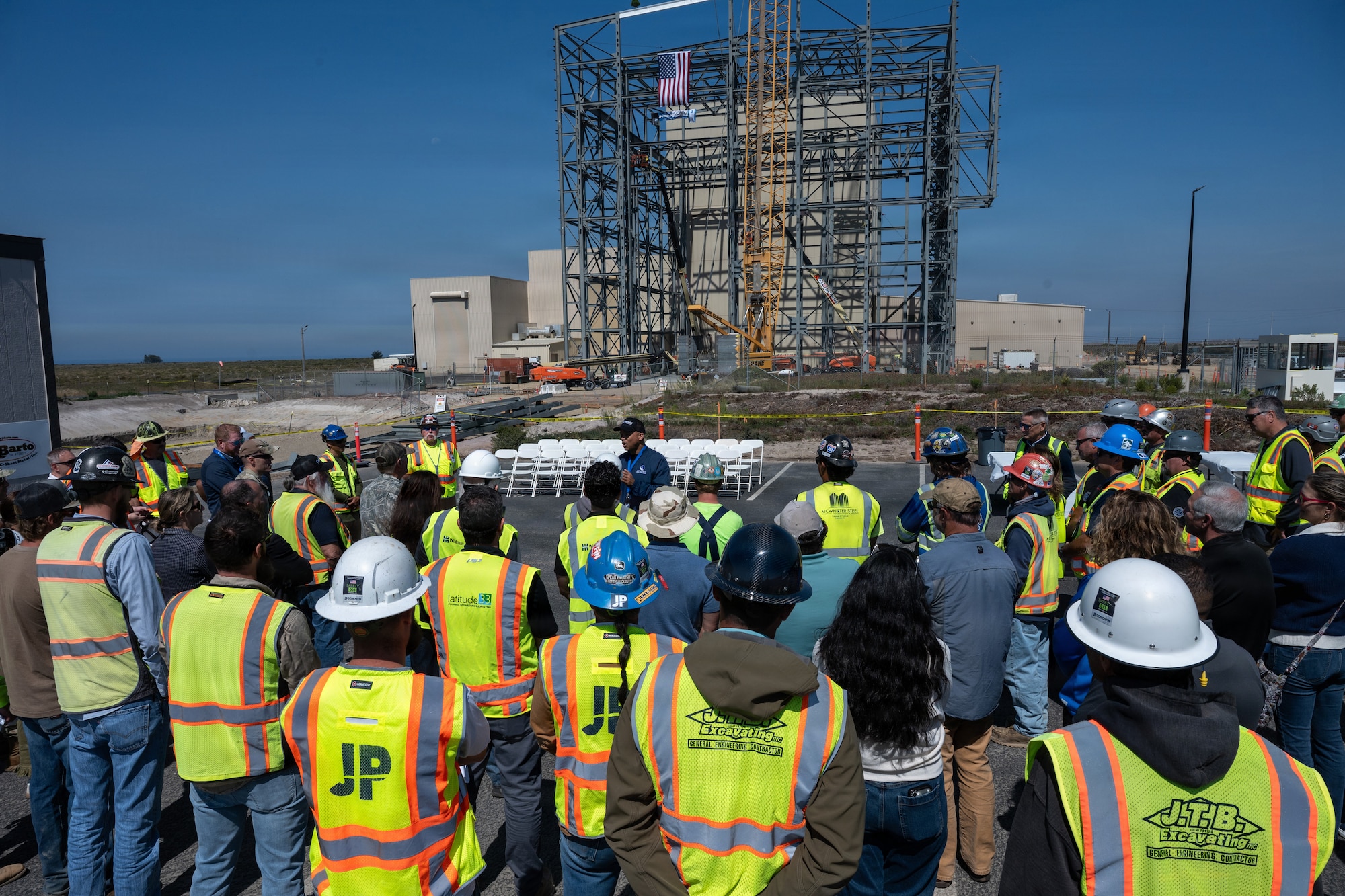 People gather to listen to a speaker at a construction site.