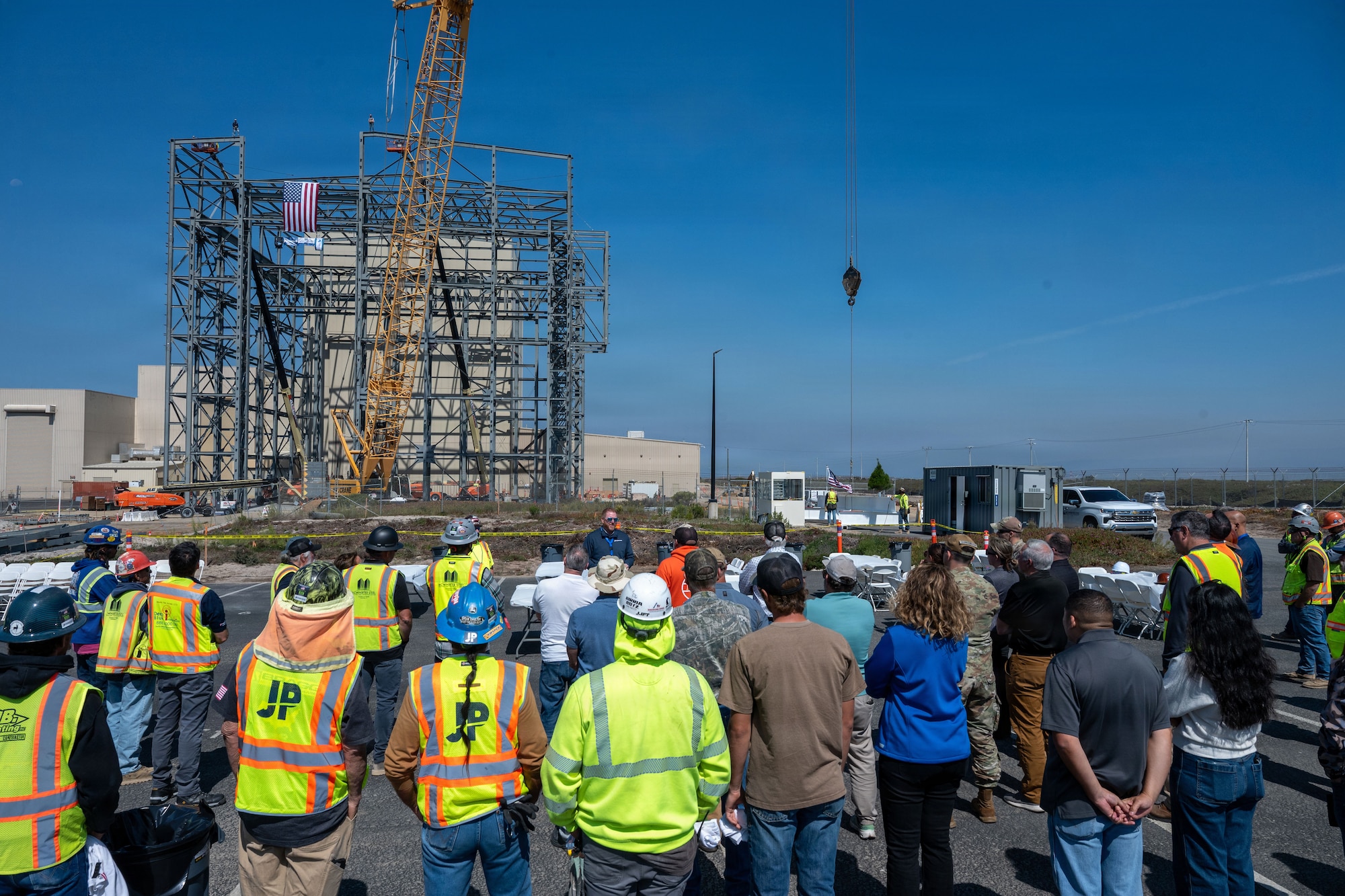 People gather around the speaker at a construction site.