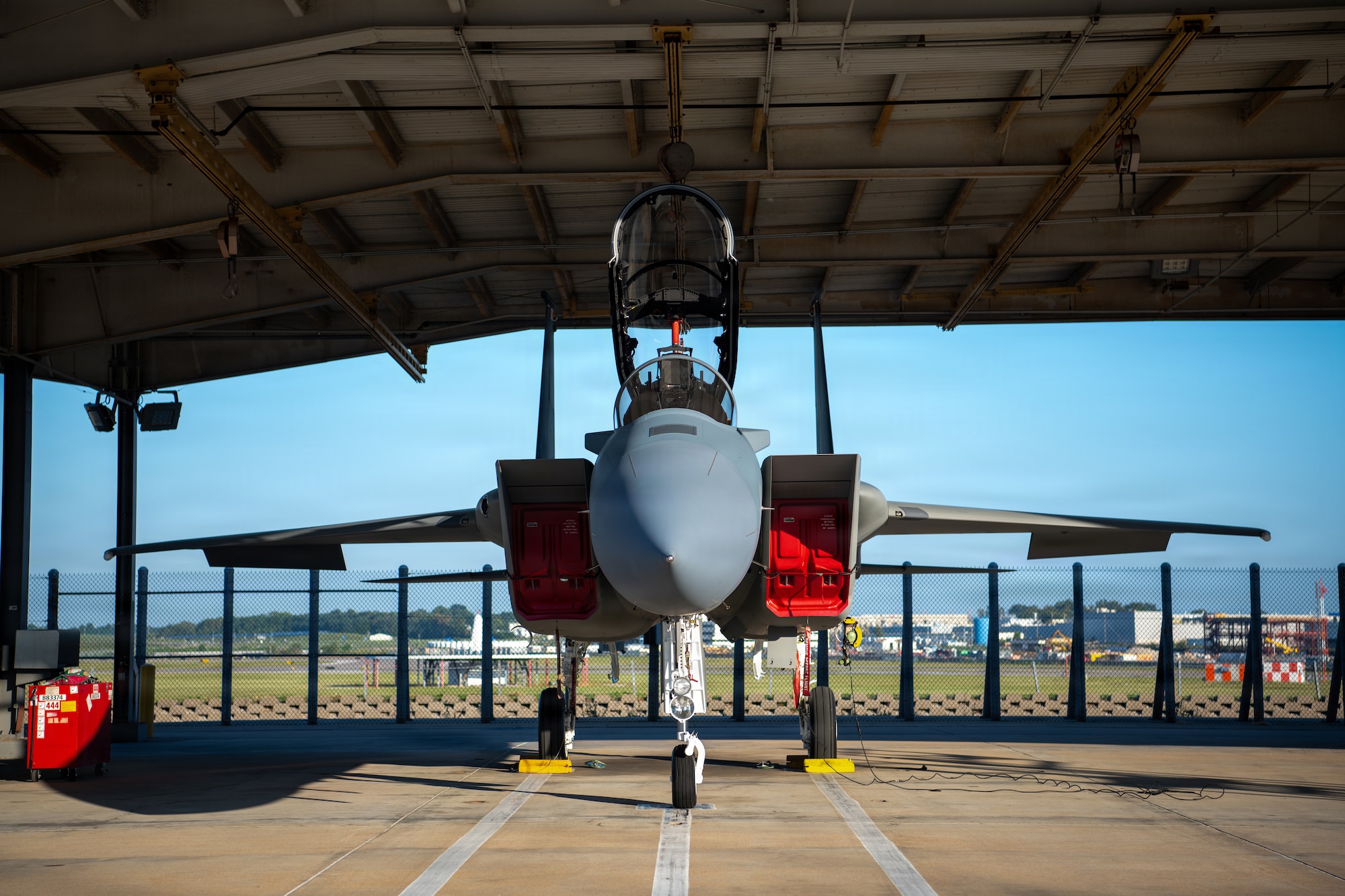 front view of the nose of a jet aircraft underneath a hangar